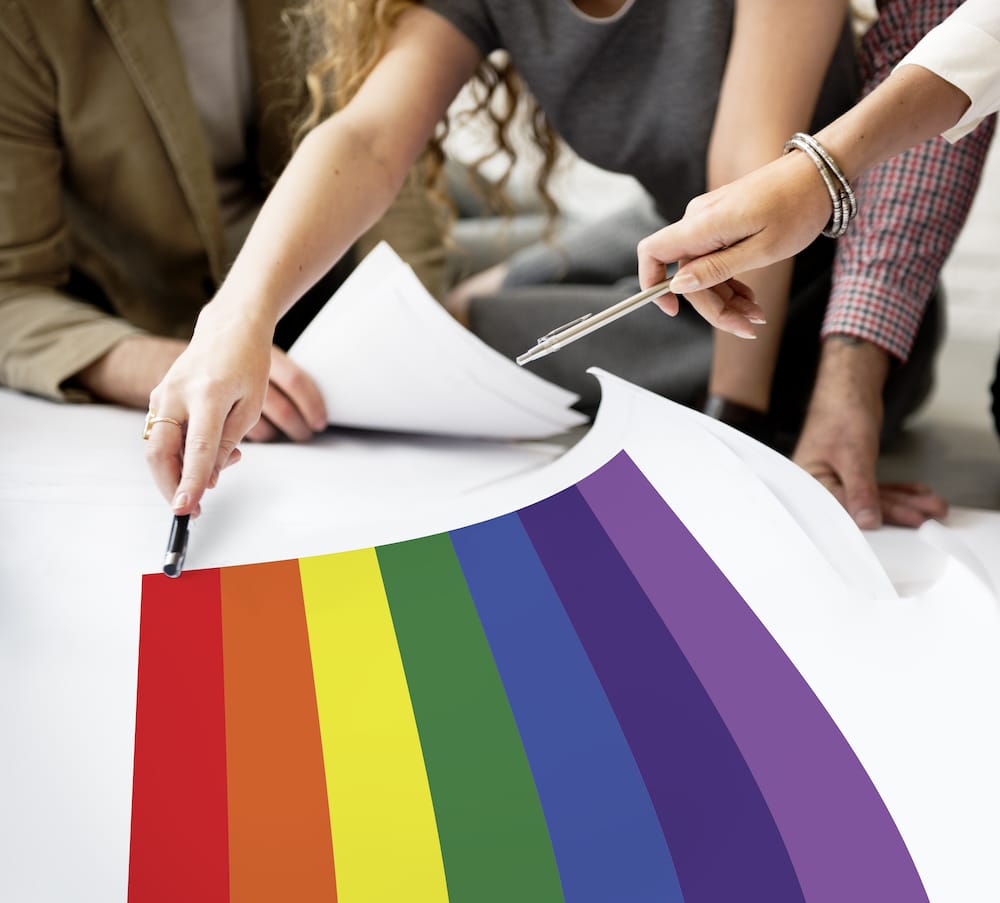 People pointing to rainbow colours on a table